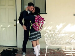 A black haired kitten is getting kissed in the yard by her schoolmate